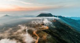 Misty hill with wind turbines on top